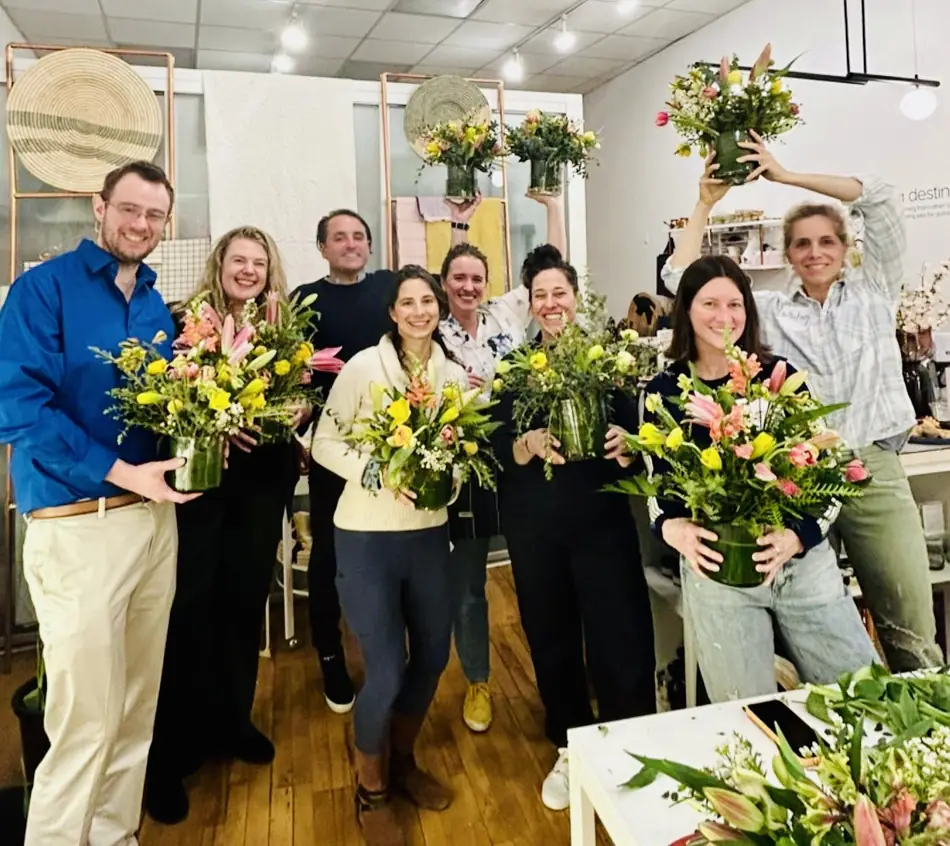 A team holding their finished arrangements after a workshop