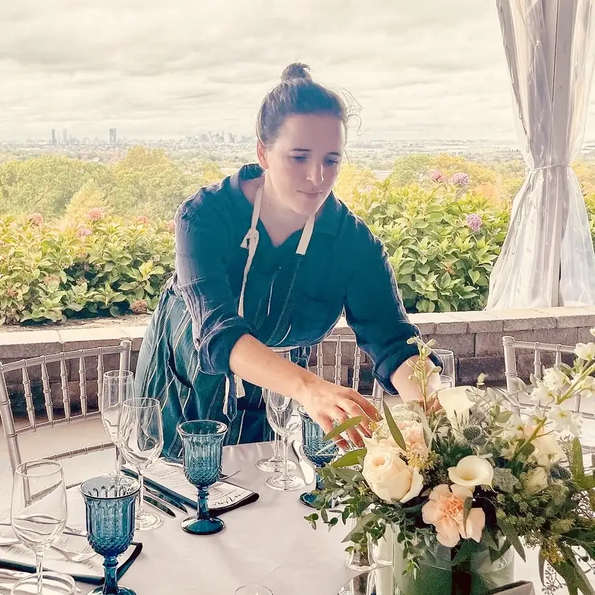 Alba setting a table with flowers at an event venue