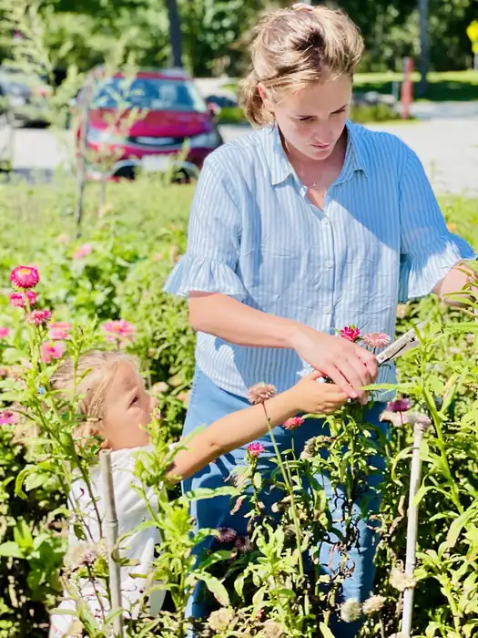 Alba cutting zinnias in a flower field with her daughter