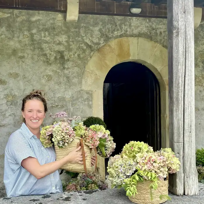 Alba with baskets of hydrangea outside a stone farmhouse