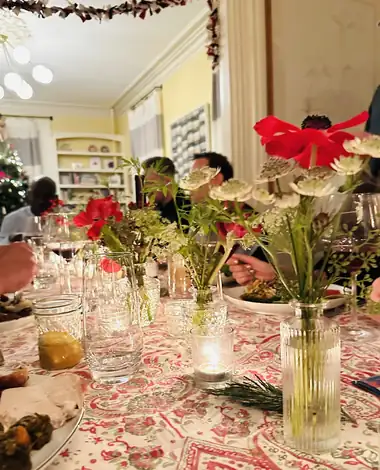 A holiday table lined with bud vases and candles