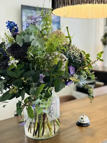 A moody arrangement of blues and greens in a glass vase