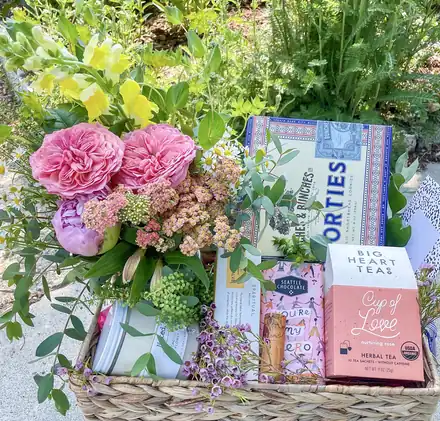A gift basket of garden roses, yarrow, tea and cookies